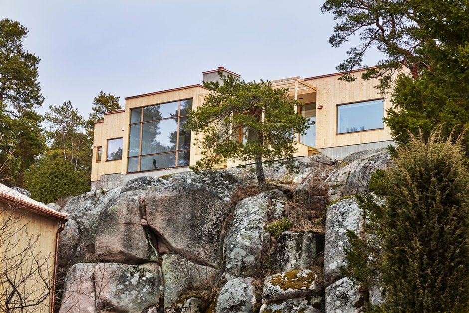 wooden house with large windows set on a cliff above the sea